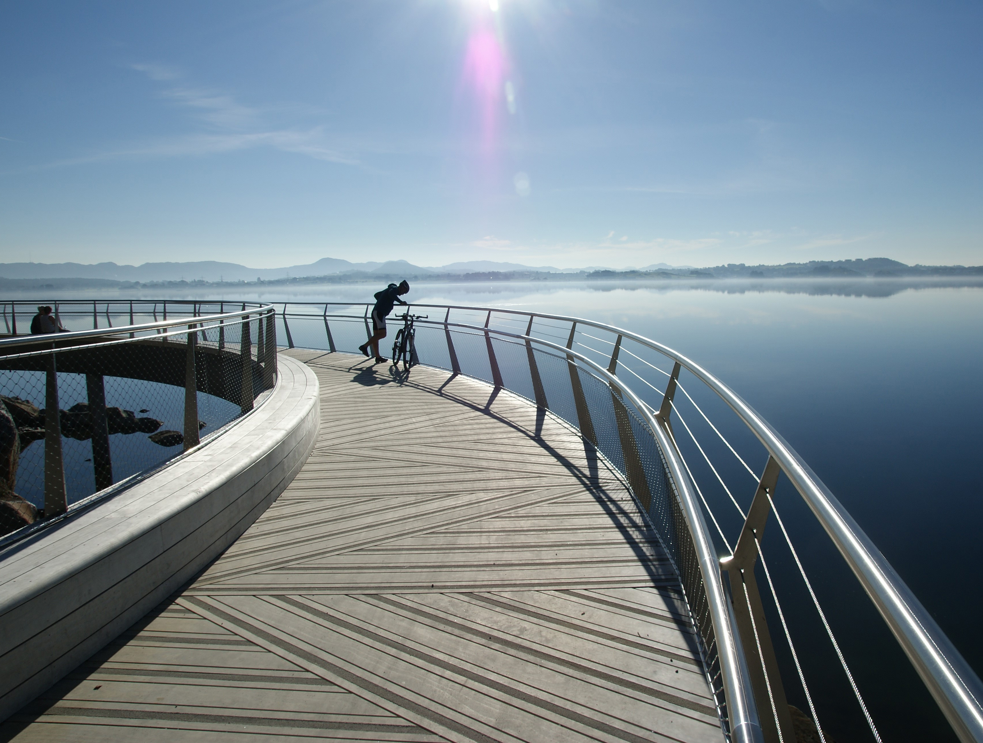 Syklist hviler på bro med fjordutsikt