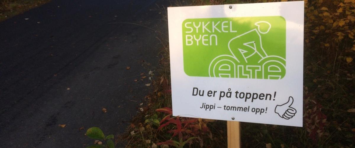 Motivasjonsskilt ved sykkelvei med teksten "Du er på toppen! Jippi - tommel opp!"