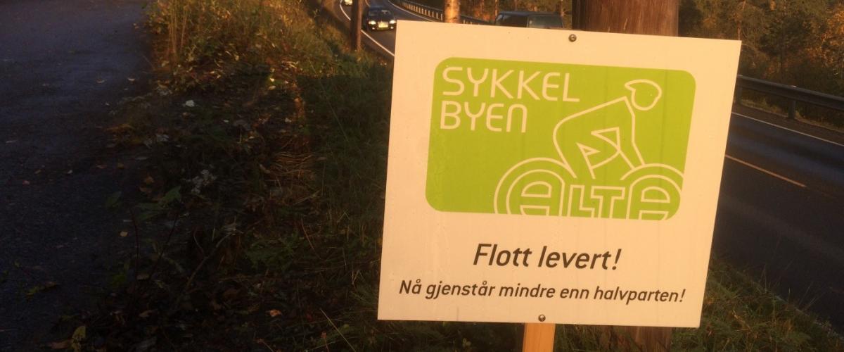 Motivasjonsskilt ved sykkelvei med teksten "Flott levert! Nå gjenstår mindre enn halvparten!"