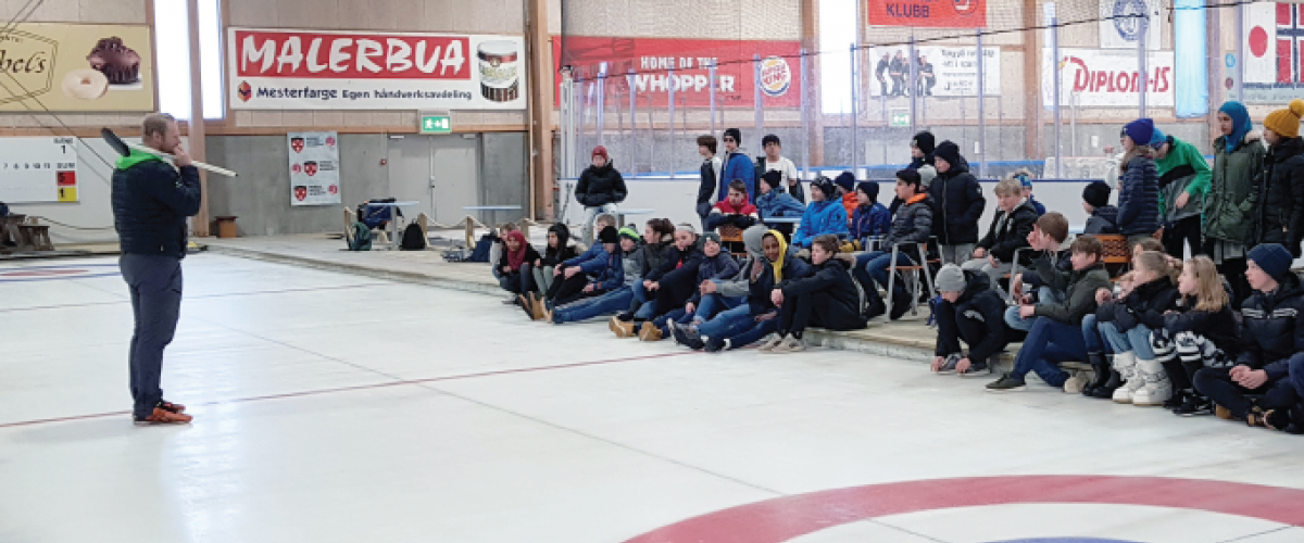 Ungdommen følger nøye med på curlingtrenerens instruksjoner