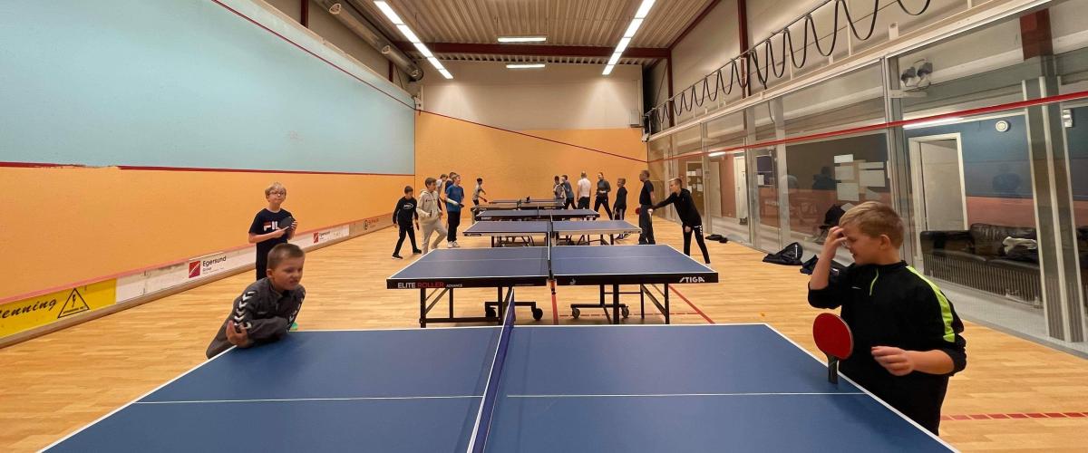 Barn som spiller bordtennis i squashhallen
