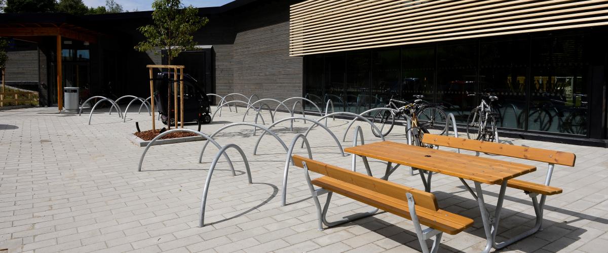 Utside av svømmeanlegg med benk og sykkelparkering