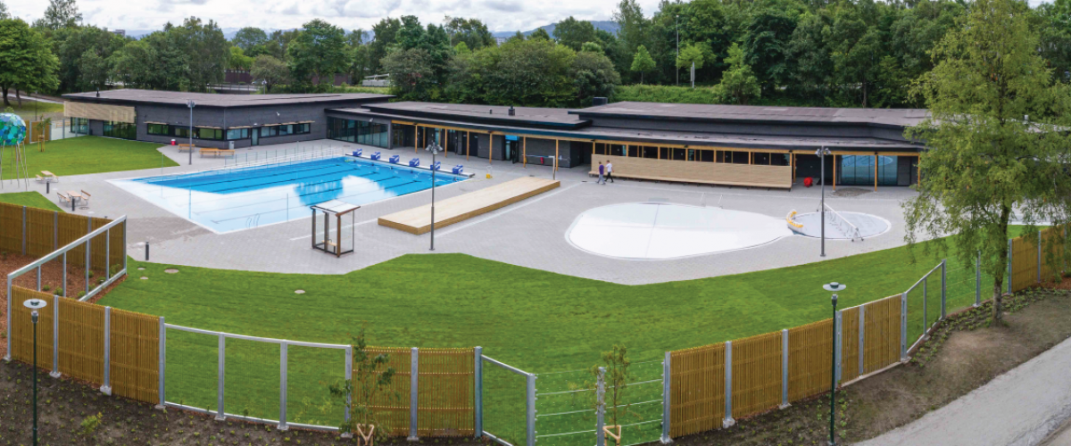 Utendørs inngjerdet svømmeanlegg med grøntområder