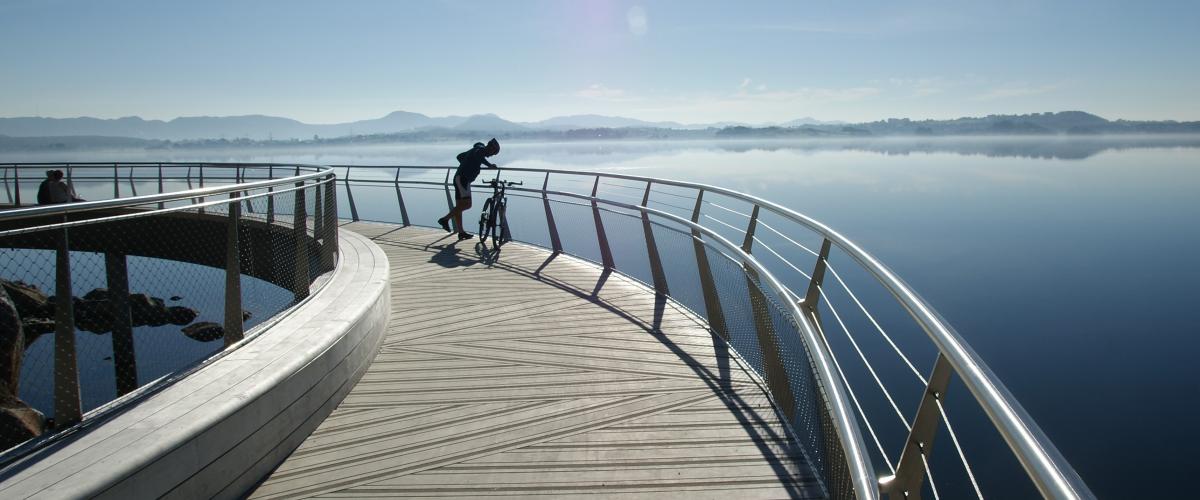 Syklist hviler på bro med fjordutsikt