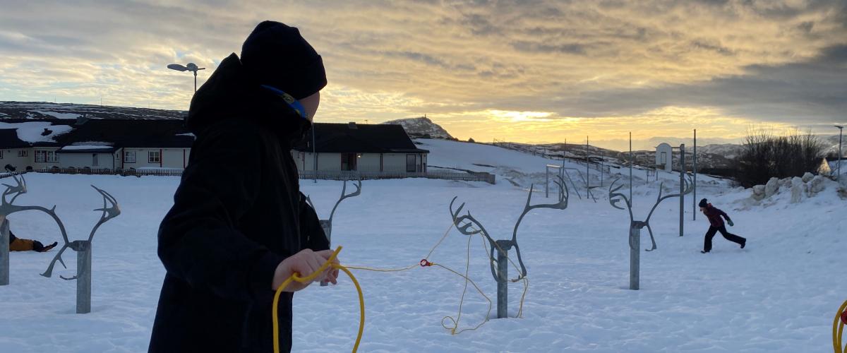 Barn laster gul lasso på reinsdyrstativ