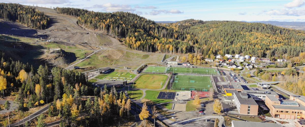 Dronefoto av Marikollen aktivitetspark i tilknytning til alpinanlegg, skole og fotballbaner.