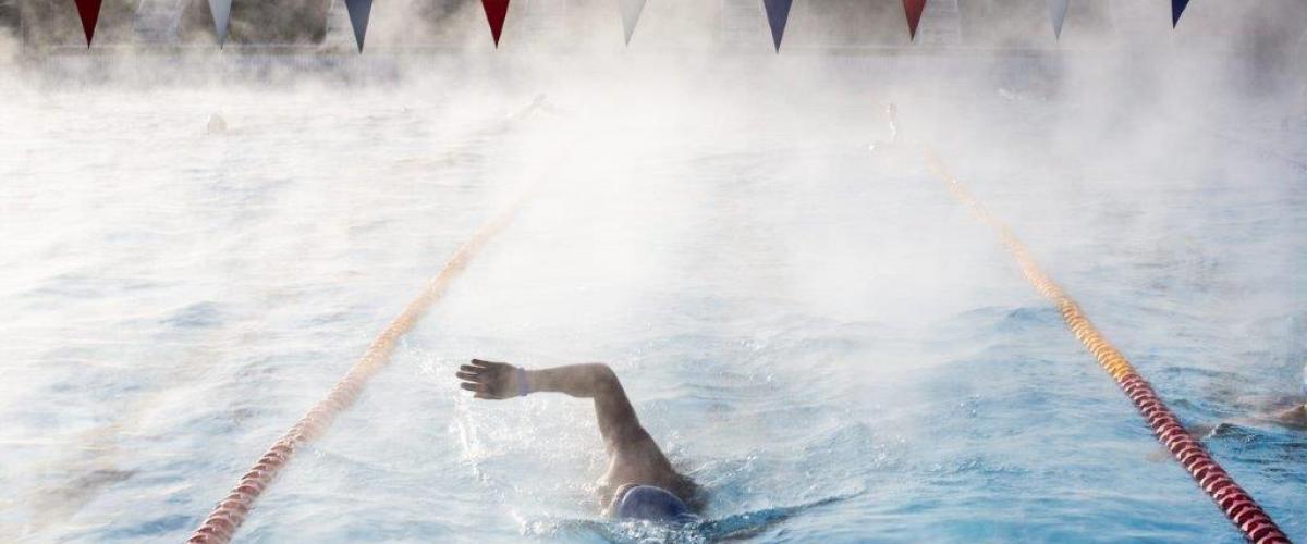 Svømmer tar svømmetak i utendørs svømmebasseng