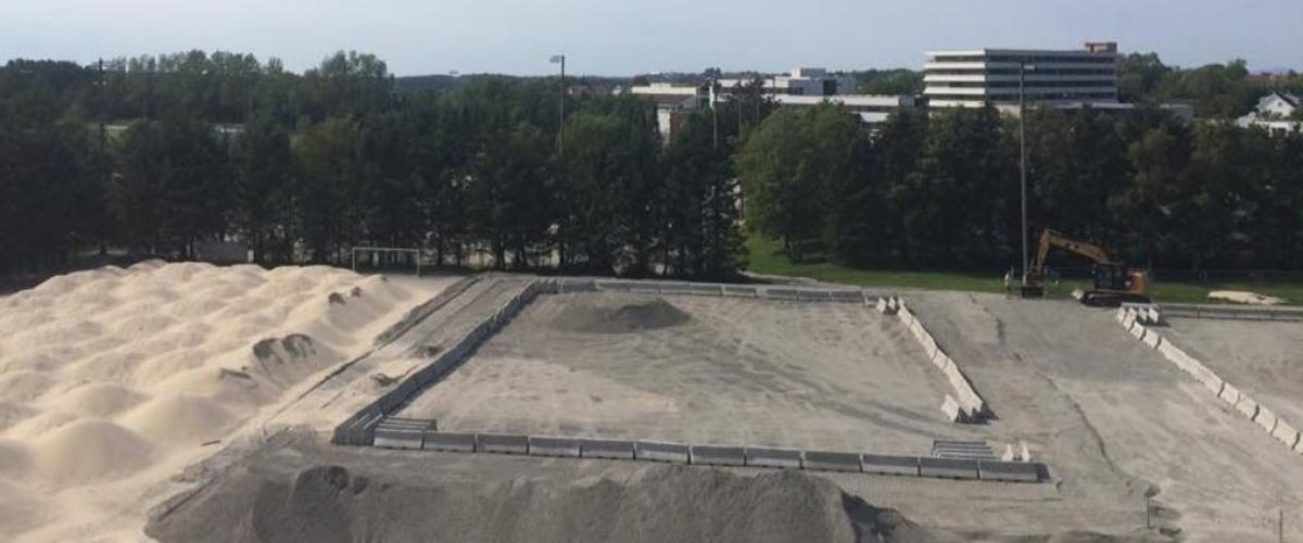 Til anlegget har det gått med 2000 tonn grus til avretting og 2700 tonn kvalitetssand til banene. Foto: Oddbjørn Kvammen Sandhauger og gravemaskin