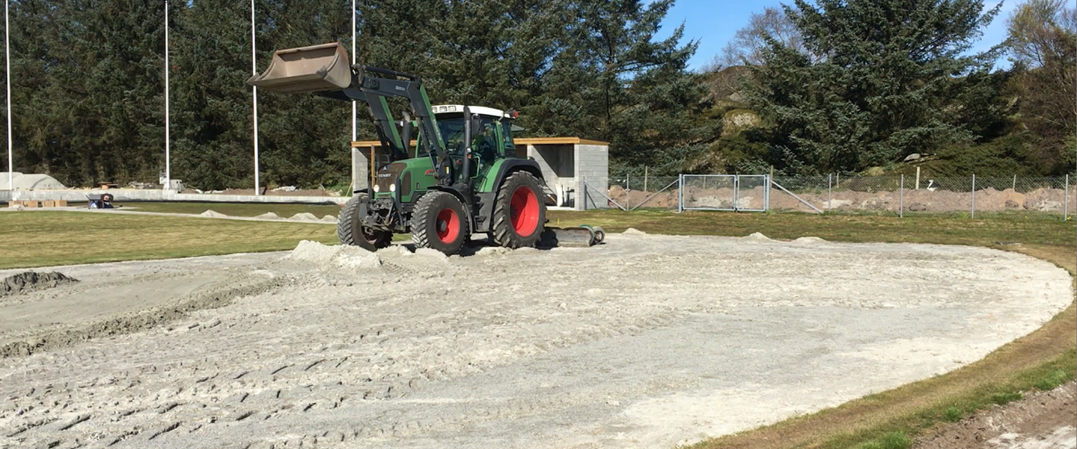 Traktor avretter sand
