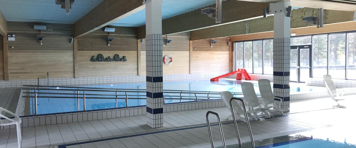 Innandørs symjehall på Tinfos bad med basseng, trepanel og store vindauge mot uteområdet.