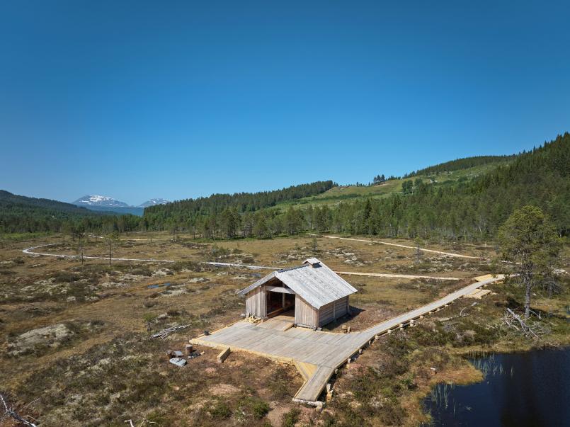 Stor tømmerbu ved Lomtjønna, med rampe og bålgrue, tilrettelagt for rullestolbrukere